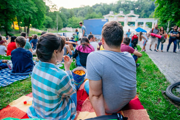 people watching movie in open air cinema in city park