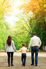 Fototapeta na wymiar Happy family having fun outdoors. Young mother, father and their son walking in the park. Happy family resting together in sunny day. Family weekend