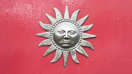 Sun with face ornament on red wall