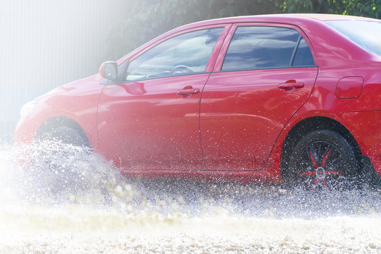 Red Car Rides On Big Puddle. Water Splash.