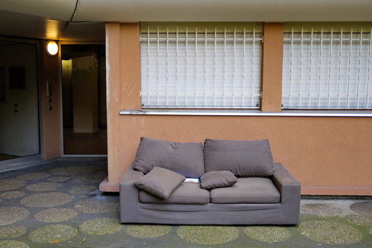 Canapé marron en tissu jeté dans la rue.