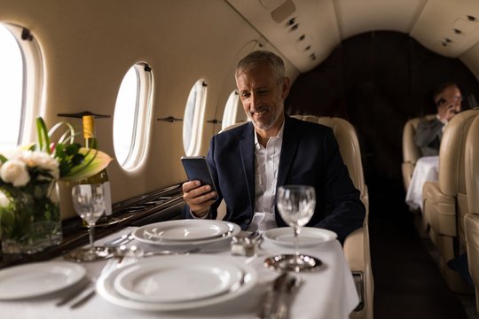 Businessman using mobile phone in private jet