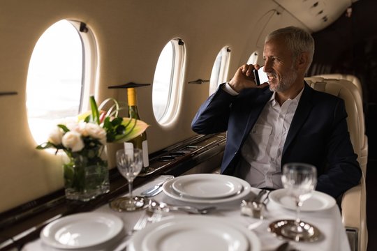 Businessman talking on mobile phone in private jet