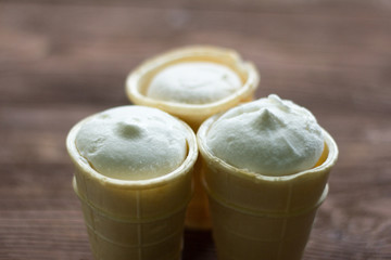 Obraz na płótnie Canvas plain white vanilla ice cream in waffle Cup on wooden background