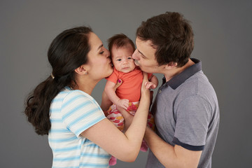 Young parents kiss small baby