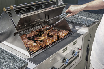 modern outdoor propane gas grill with man turning stakes