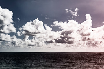 dramatic clouds over a calm sea on a sunny day. toned