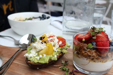 breakfast at a restaurant yogurt fruits bowls and cheese / avocado on toast