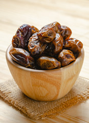 dried dates plam fruit in wooden bowl on table