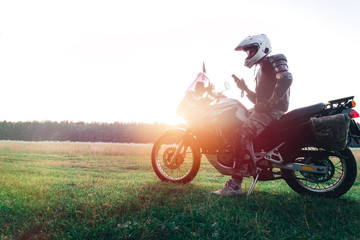 Man stand with tourist motorcycle outdoor sunset, use smart phone, copy space, travel concept
