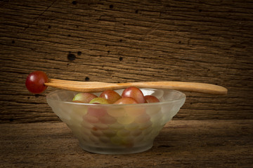 grapes red in bowl glass. grapes red on fork. on old wood