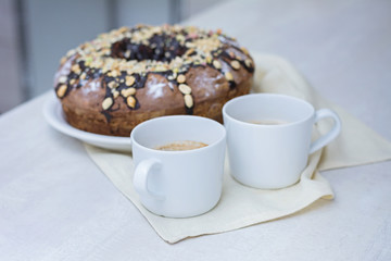Homemade cake with nuts and chocolate and two cups of coffee on wooden white table