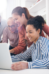 Three business people around a laptop