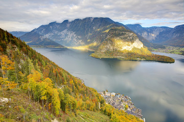 Aerial view of Hallstatt village by the lake and colorful fall mountains lighted up by beams of sunlight on a brisk autumn day, an amazing lakeside village in Salzkammergut region of Austria