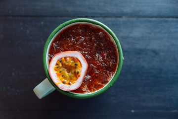 Top view of Iced Passion fruit juice served in zinc cup with a cut half of fresh passion fruit.