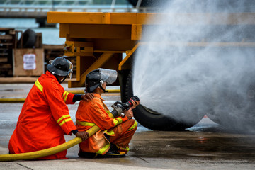 Fireman using water and extinguisher to fighting with fire flame in an emergency situation Car crash .under danger situation all firemen wearing suit for safety.