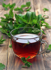 A cup of herbal tea, decorated with leaves. Close-up. Natural drink on a wooden background. Selective focus.