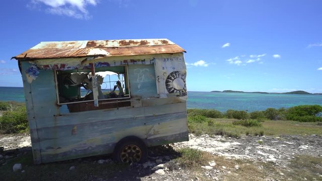 Apocalyptic tropical landscape. Old lonely caravan wreck on the beach