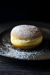 Fresh home donute on a brown plate sprinkled with powdered sugar.