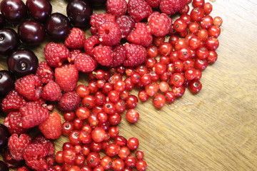 Photo of cherry, red currant and raspberries on wooden table