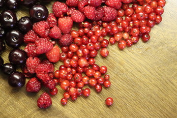 Photo of cherry, red currant and raspberries on wooden table