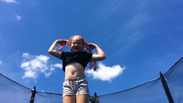 carefree childhood, happy summer. beautiful girl with African pigtails jumping on a trampoline - slow motion