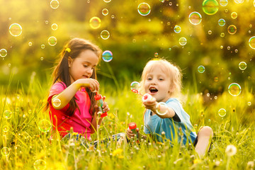 Little girls blowing soap bubbles with her grandmother outdoors