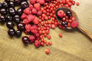 Photo of cherry, red currant and raspberries on wooden table