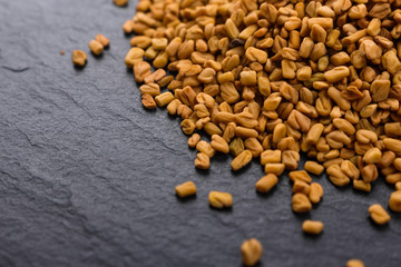 fragrant grains of fenugreek on a rustic background