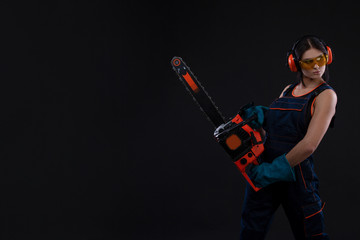 young woman with motor saw or chainsaw on a black background