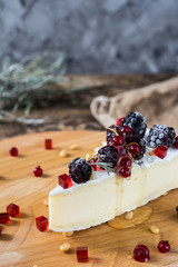 French cheese brie, camambert with honey, marmalade and pine nuts on wooden cheese board. Berries marmalade and honey in motion with honey dipper.