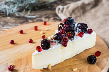 French cheese brie, camambert with honey, marmalade and pine nuts on wooden cheese board. Berries...