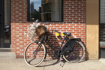 bicycle bike flowers in basket parked against wall background brick wall of NYC shop