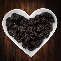 Dried Plums Pitted Prunes in Heart Shaped Bowl. Selective focus.