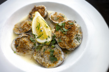 breaded stuffed baked clams on a half shell dish with butter and lemon wedge 