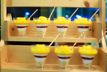 Selective focus photo of Seasonal Tropical Mango Fruit creamy trifle in beautiful glasses with fresh ripe fruit slices on table background. Delicious Healthy vegetarian dessert.