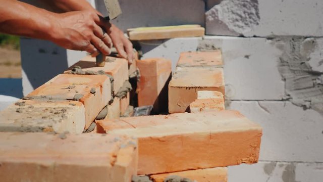 The hands of the worker, makes brick masonry