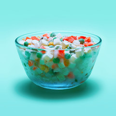 Bowl with frozen vegetables on a green background