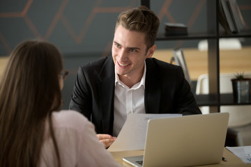 Smiling male recruiter or employer talking to female applicant, discussing her resume during...