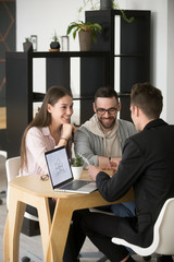 Architect or designer discussing house plan with excited millennial buyers couple visiting his...