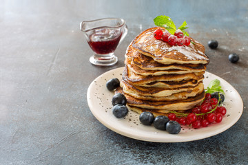 Pancakes and fresh berries on grunge stone background