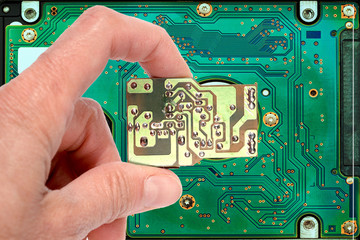hand holds a techno key on the background of the motherboard