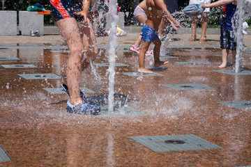 Children bathe in the fountain between the jets. Summer in the city.