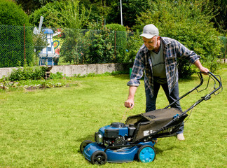 Mann mittleren Alters beim  Rasenmähen in seinem Garten