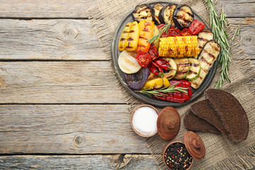 Grilled vegetable on brown cutting board with salt, pepper and bread