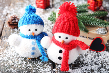 Small snowman toys and wooden sleigh with fir-tree branches on grey table