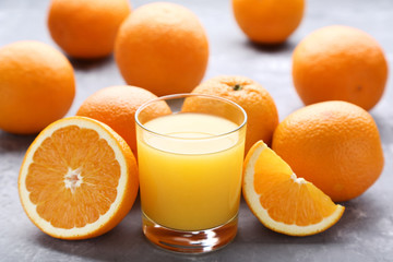 Orange fruit with glass of juice on grey wooden table