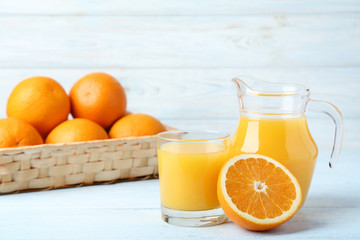 Orange fruit with jug and glass of juice on wooden table