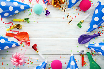 Birthday party caps, blowers and balloons on wooden table