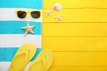 Summer accessories with seashells on yellow wooden table